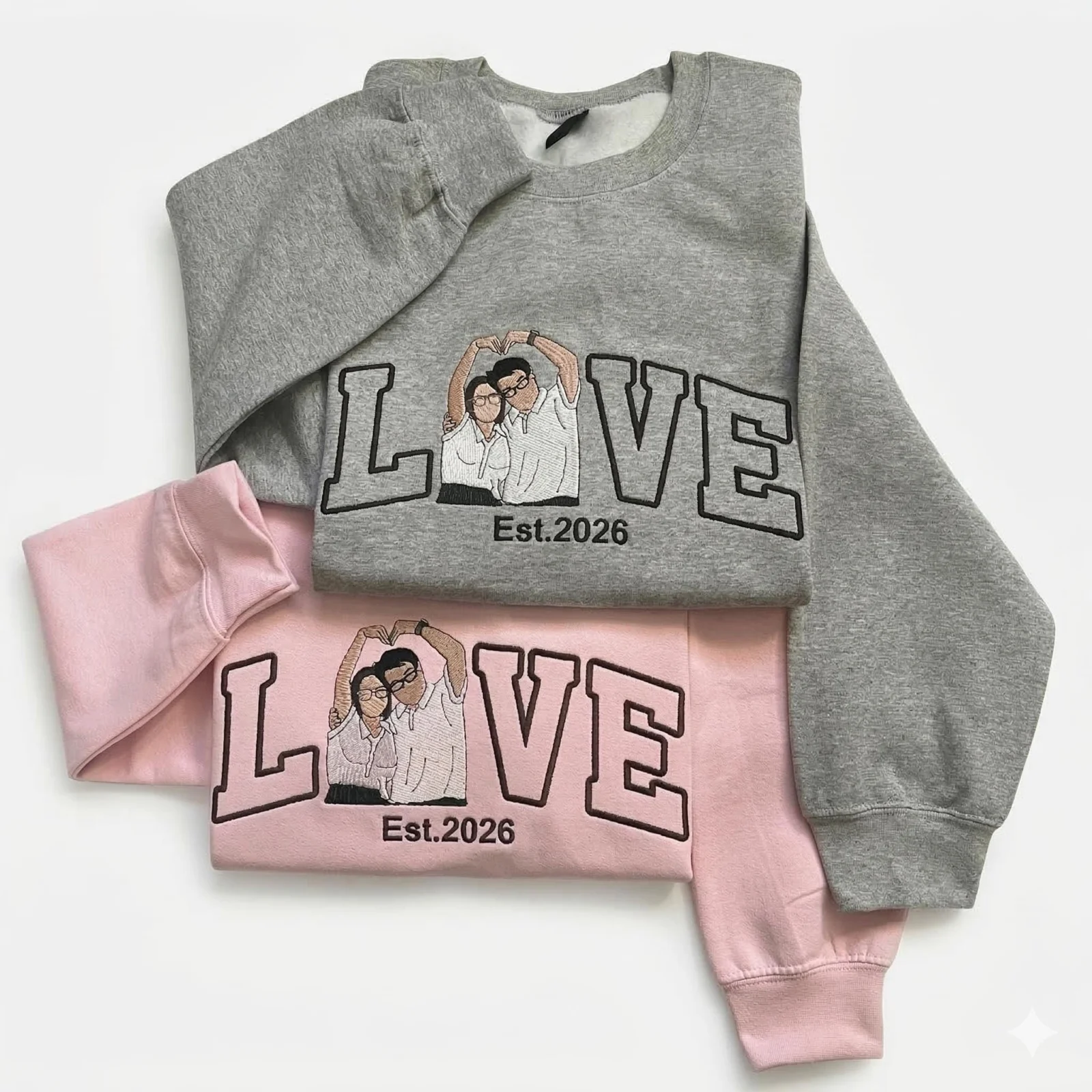 Grey and light pink sweatshirts with outline LOVE letters, a couple portrait making a heart in place of the O, Est.2026