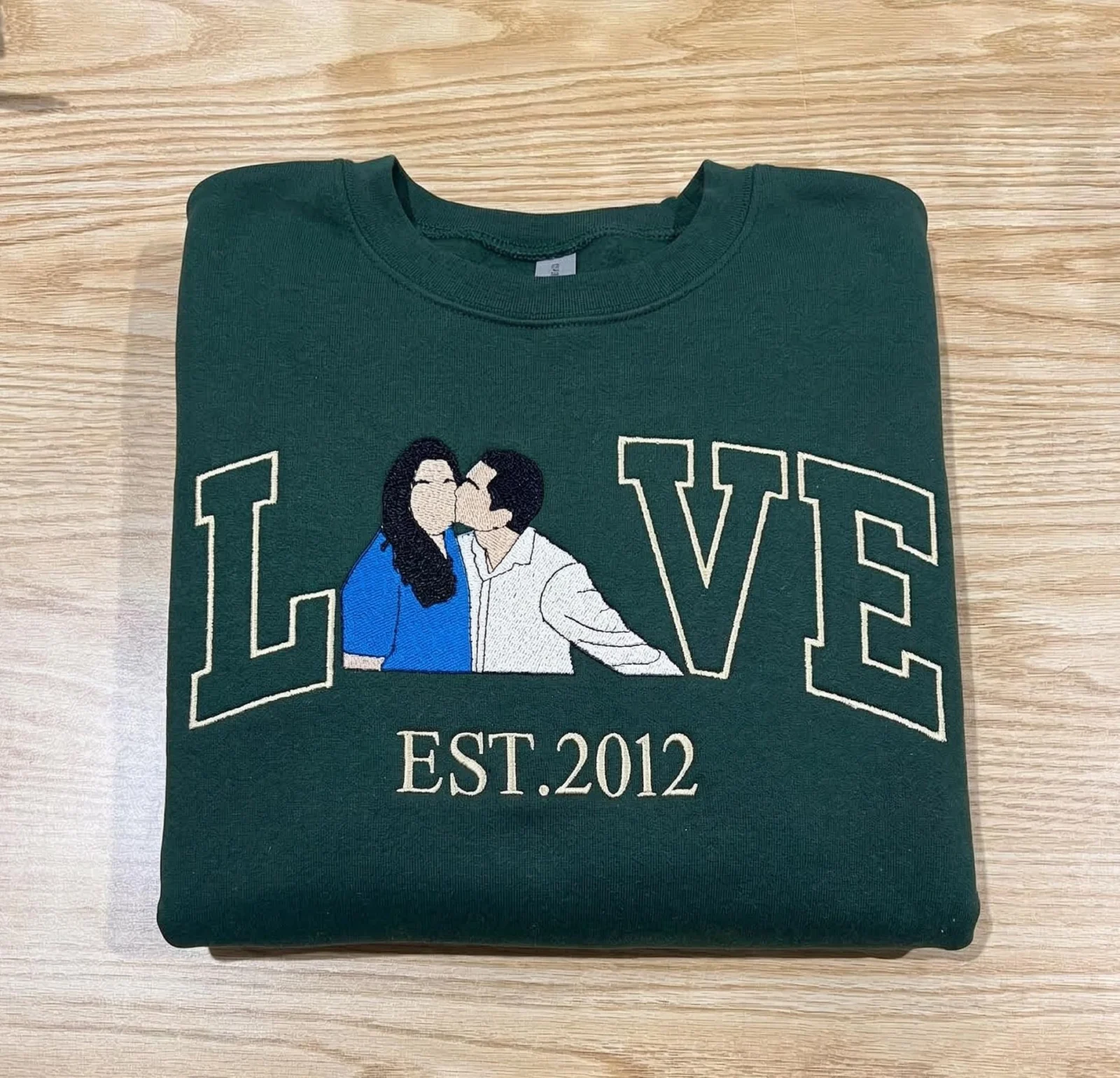 Forest green sweatshirt with LOVE in outline letters, a kissing couple portrait as the O and EST.2012 below