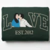 Folded forest green crewneck with the kissing couple LOVE portrait embroidery and EST.2012 in cream thread