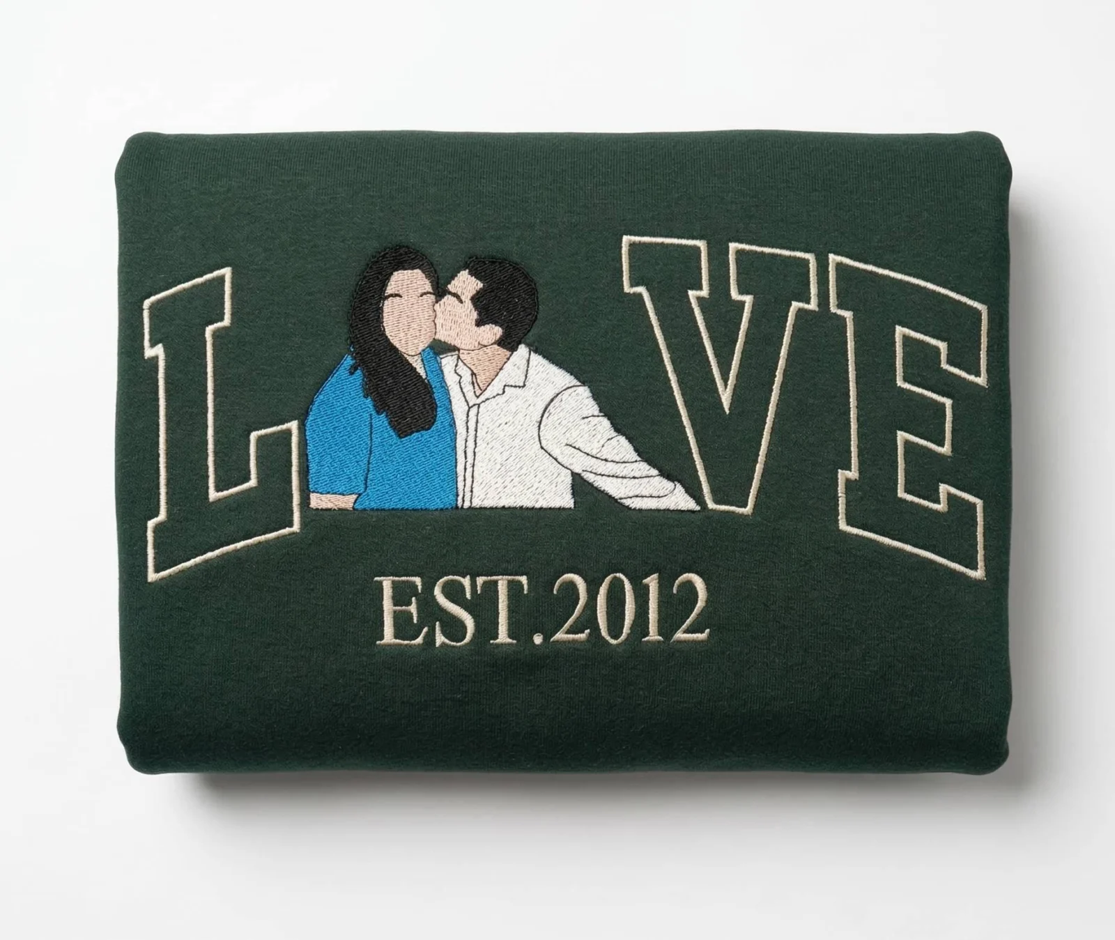 Folded forest green crewneck with the kissing couple LOVE portrait embroidery and EST.2012 in cream thread
