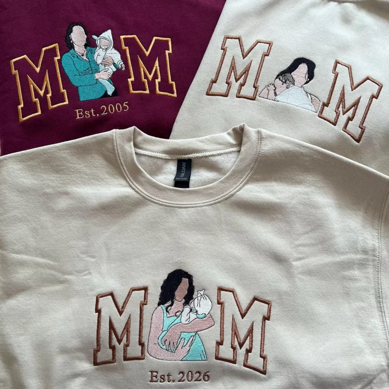 Maroon and two sand sweatshirts with outline MOM letters, each O replaced by a stitched mom holding her baby
