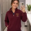 Nurse taking a mirror selfie in a maroon quarter-zip embroidered with Olivia, RN and Registered Nurse