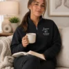 Woman relaxing with a mug and book in a black quarter-zip with name and RT credential embroidered in white