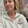 Teacher in a classroom wearing an ash quarter-zip with an embroidered apple and Ms. Meagan on the left chest