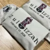 Angled pair of sand hoodies with the embroidered couple, Zul and Izzah, the date, and a letter Z with a cat on the cuff