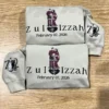 Two light sand hoodies with a couple in maroon wedding outfits, the names Zul and Izzah and February 07, 2026