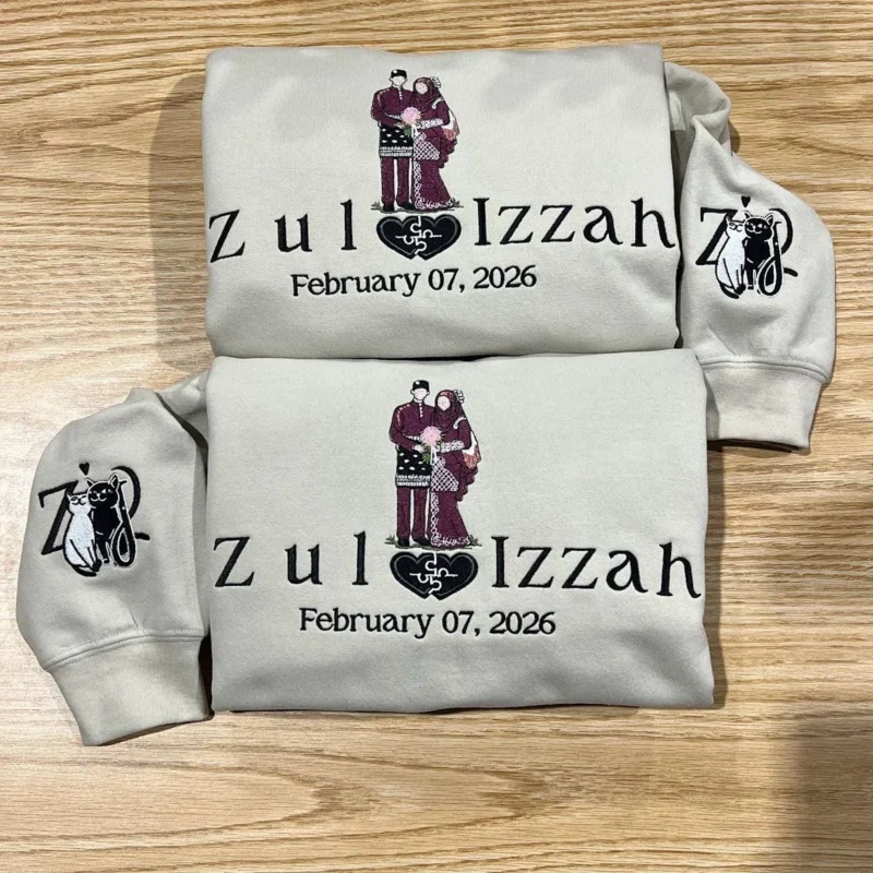 Two light sand hoodies with a couple in maroon wedding outfits, the names Zul and Izzah and February 07, 2026