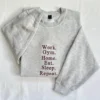 Ash grey sweatshirt with Work. Gym. Home. Eat. Sleep. Repeat. stacked in maroon serif embroidery, flat-lay